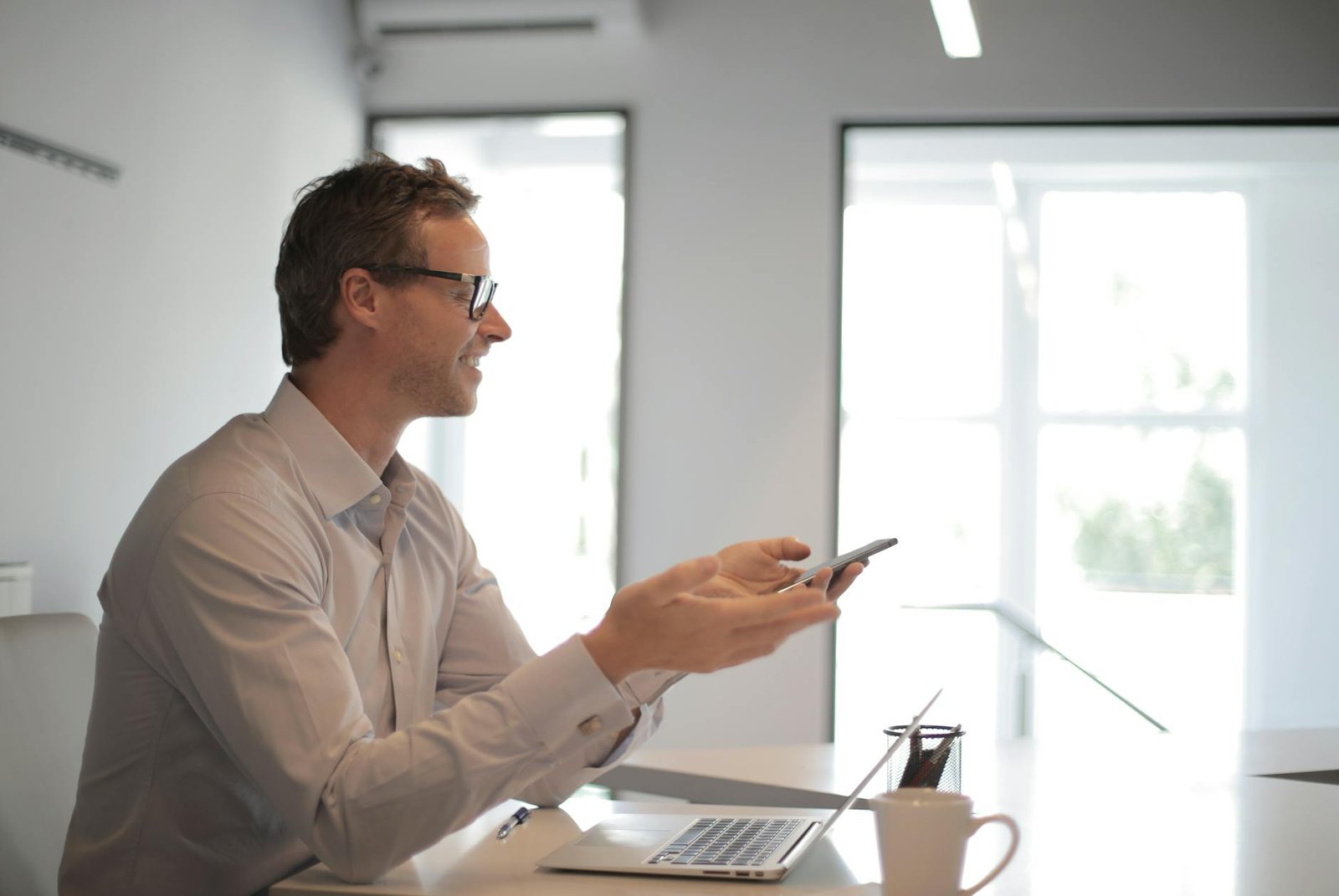 smiling adult businessman at table with gadgets holding presentation